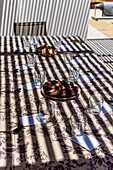 Outdoor dining setup with shadows and food on patterned tablecloth