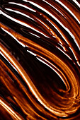 Wavy texture of melted chocolate with shiny highlights