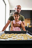 Father and daughter prepare biscuits in a modern kitchen