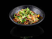 Sizzling Asian stir-fry with beef and vegetables in a black bowl