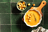 Pumpkin soup with croutons on a rustic wooden board