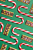 Top view of candy canes and decorated butter cookies on green background