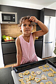 Young girl preparing decorated biscuits in the kitchen