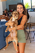 Cheerful woman holding a dog in a lively indoor environment