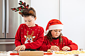 Zwillinge backen Weihnachtsplätzchen in festlicher Kleidung