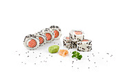 Salmon sushi rolls with black sesame seeds on white backdrop