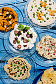 Various Mediterranean dips on blue plates in the open air