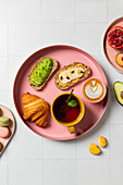 Eleganter Frühstücksaufstrich mit Gebäck und Obst auf rosa Tellern