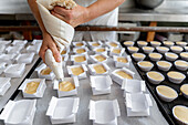 Chef preparing pastries with a piping bag in a bakery