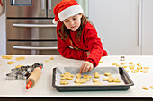 Young girl in festive clothes bakes Christmas biscuits