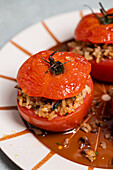 Roasted stuffed tomatoes with brown rice and nuts on a ceramic plate