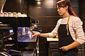 Barista prepares coffee in a cosy café