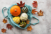 Autumnal composition with various pumpkins in an eco string bag