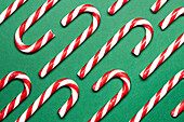 Top view of red and white candy canes on a green surface