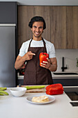 Smiling man pointing at a red pepper standing in a modern bakery