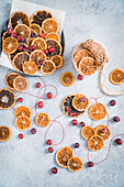 Bastelzubehör mit getrockneten Orangenscheiben, Cranberries und Garn für Weihnachtsdekoration