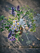 Wildblumenstrauß mit Lavendel und Aster auf Steinboden im Frühsommergarten