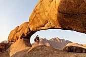 Namibia, Erongo province, Spitzkoppe, tourists under the arch