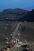 Spanien, Kanarische Inseln, Insel Palma, Punta de Fuencaliente, Wanderer auf einem Lavafeld mit Blick auf den Ozean