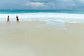 Seychellen, Insel La Digue, Schwimmer in den Wellen am Strand der Bucht