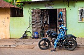 Benin, Ouidah, biker in front of a garage