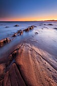 Frankreich, Var, Saint-Raphaël, Sonnenuntergang Lichter auf den Felsen von Péguière Strand mit dem Massif des Maures im Hintergrund