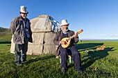 Kyrgyzstan, Naryn Province, Son-Kol Lake, altitude 3000m, Kyrgyz man playing the guitar in front of a yurt