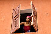 Benin, Abomey, woman opening window of Abomey museum