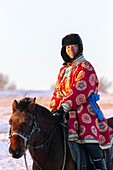 China, Inner Mongolia, Hebei Province, Zhangjiakou, Bashang Grassland, one Mongolian horseman on a horse running in a meadow covered by snow