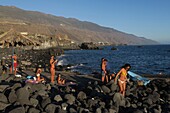 Spain, Canary Islands, Palma Island, Playa la Bombilla, young people in swimwear on a pebble beach