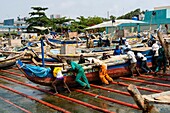 Benin, Cotonou, Fish market, fishermen getting back their repaired boat into the water