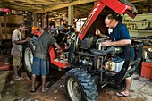 Papua New Guinea, East Sepik Province, Sepik River Region, Angoram District, Samban Village, US Missionary Jesse Pryor fixing his tractor