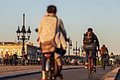 France, Gironde, Bordeaux, area listed as World Heritage by UNESCO, cyclists on the Pont de Pierre over the Garonne, brick and stone vaulted bridge inaugurated in 1822 and in the background the church of Sainte-Marie-de- la-Bastide