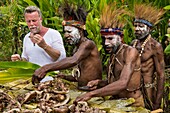 Papua New Guinea, Simbu Province, Kagaï village, Pagau Tribe, preparation of a traditionnal feast called Mumu during which a pig is stewed with white-hot stones in buried banana leaves, documentary filming with german journalist and traveller Jenke von Wilmsdorff