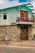 Ecuador, Galapagos archipelago, listed as World Heritage by UNESCO, San Cristóbal Island, Puerto Baquerizo Moreno, a woman walks past a house with a balcony made of old American military pieces, vestiges of the base installed on the island of Baltra to respond to a possible Japanese attack during the Second World War