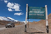 Tajikistan, Gorno-Badakhshan Autonomous Region, Ak-Baital Pass, altitude 4655m, Pamir Highway, Tajik National Park and Pamir Mountains, UNESCO World Heritage Site, track, jeep and Cyrillic sign announcing the altitude of the pass