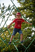 Young boy climbing on a spider web