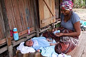 Madagascar, Diana region, village of Marosely, a woman dresses her baby in front of her house