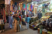 Egypt, Upper Egypt, Aswan, Egyptians wandering between stands of spices and colorful clothes in a covered alley of the souk