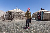 Tajikistan, Gorno-Badakhshan Autonomous Region, Yurt camp by M41 road, also called Pamir Highway, Kyrgyz girl posing in front of yurts and mother in the background, altitude 3900m