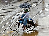 Myanmar, cyclist under the rain in the streets of Rangoon