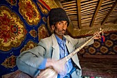 China, Xinjiang autonomous region, Sanju, shepherd with astrakan hat playing the dôtar, or traditional luth