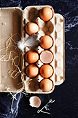 Fresh eggs in a carton on a black marble background