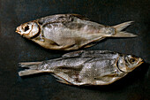 Pile of sun-dried sea fish sea bream on dark textured background. Salty traditional starter. Seafood background