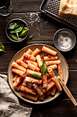 Plate of macaroni (maccheroni) with tomato sauce, on a dark wooden background. Italian food. View from above