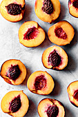 An overhead view of halved peaches showcasing their vibrant orange flesh and dark brown pits on a light textured surface.