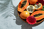 Exotische tropische Früchte,Passionsfrüchte und Drachenfrüchte,reife Papayas. auf einem Bambustablett mit grünen Blättern,steinerner Hintergrund