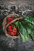 Top view of a basket full of red fresh sicilian tomatoes and beet leafs.