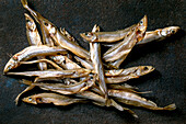 Pile of sun-dried sea fish smelt ham anchovy on a dark textured background. Salty traditional starter. Seafood background