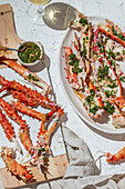 Delicious crab legs garnished with fresh herbs and garlic serve as the focal point of this mouth-watering dish. Paired with white wine, this gourmet meal is both visually appealing and full of flavors